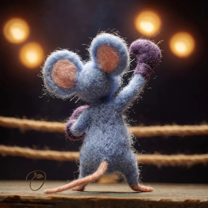 Blue plush mouse toy standing on a wooden platform with blurred lights in the background