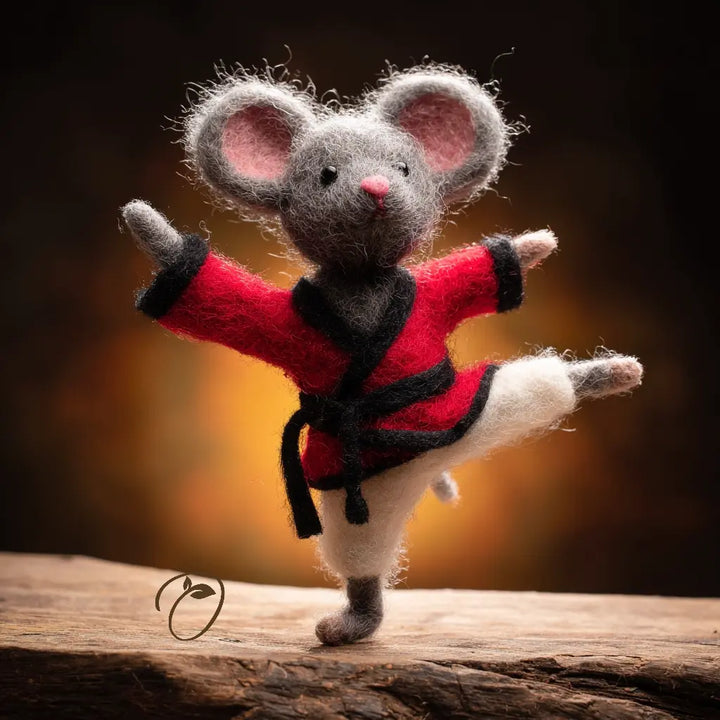 Felted mouse figurine in a red outfit with black accents on a wooden surface.