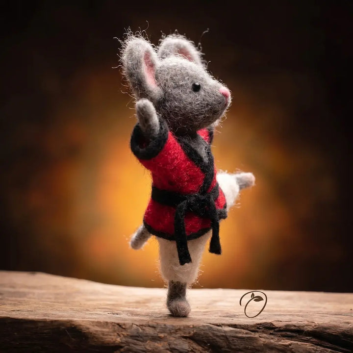 Toy mouse in a red coat waving on a wooden surface with a warm gradient background