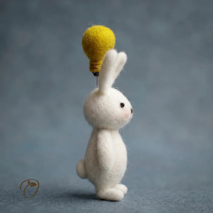 White rabbit figurine with a yellow light bulb on its head against a gray background