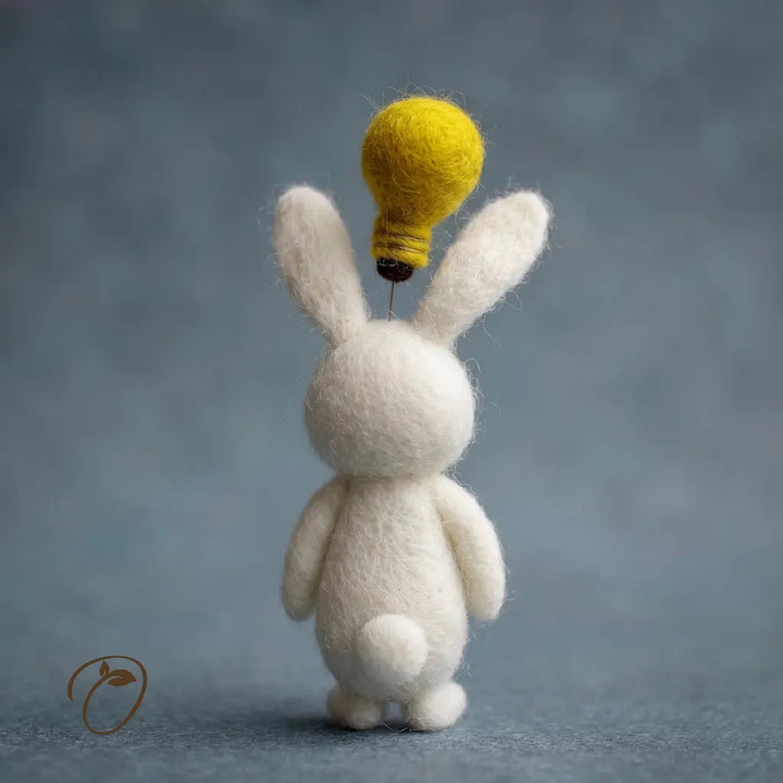 White rabbit figurine with a yellow light bulb on its head against a gray background