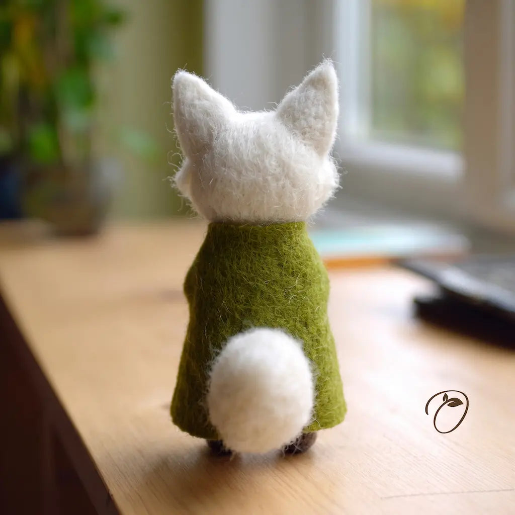 Small plush fox figurine wearing a green sweater on a wooden surface with a blurred background