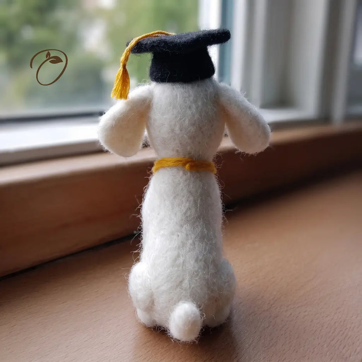 White dog figurine with a graduation cap on a wooden surface.