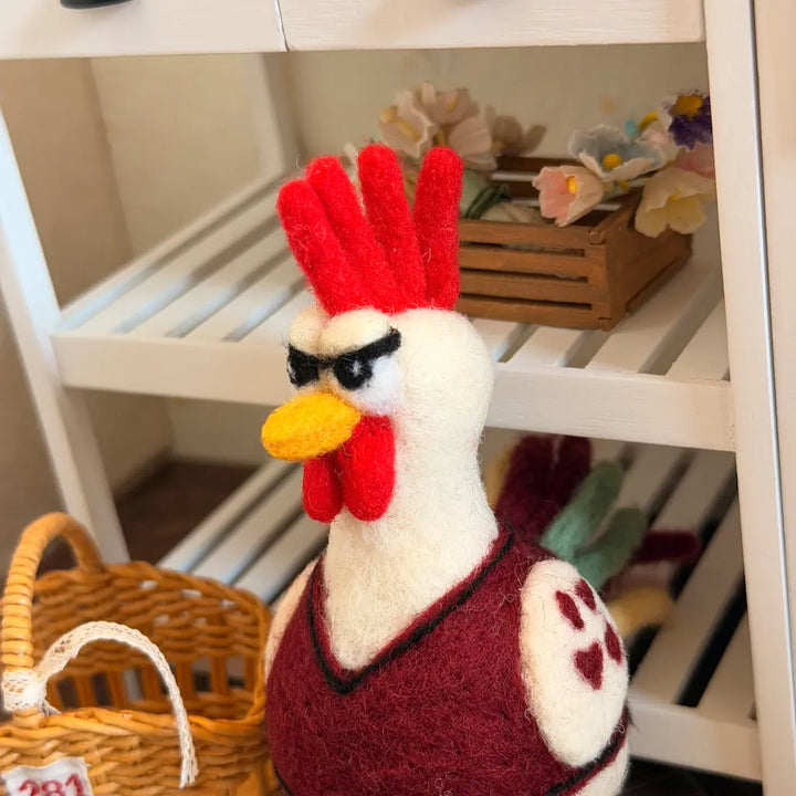 Rooster figurine with a red comb in front of a white shelf with toys.