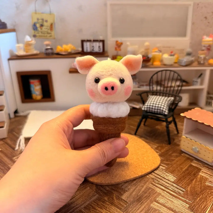 Small pig figurine in an ice cream cone held by a hand, with a room interior in the background.