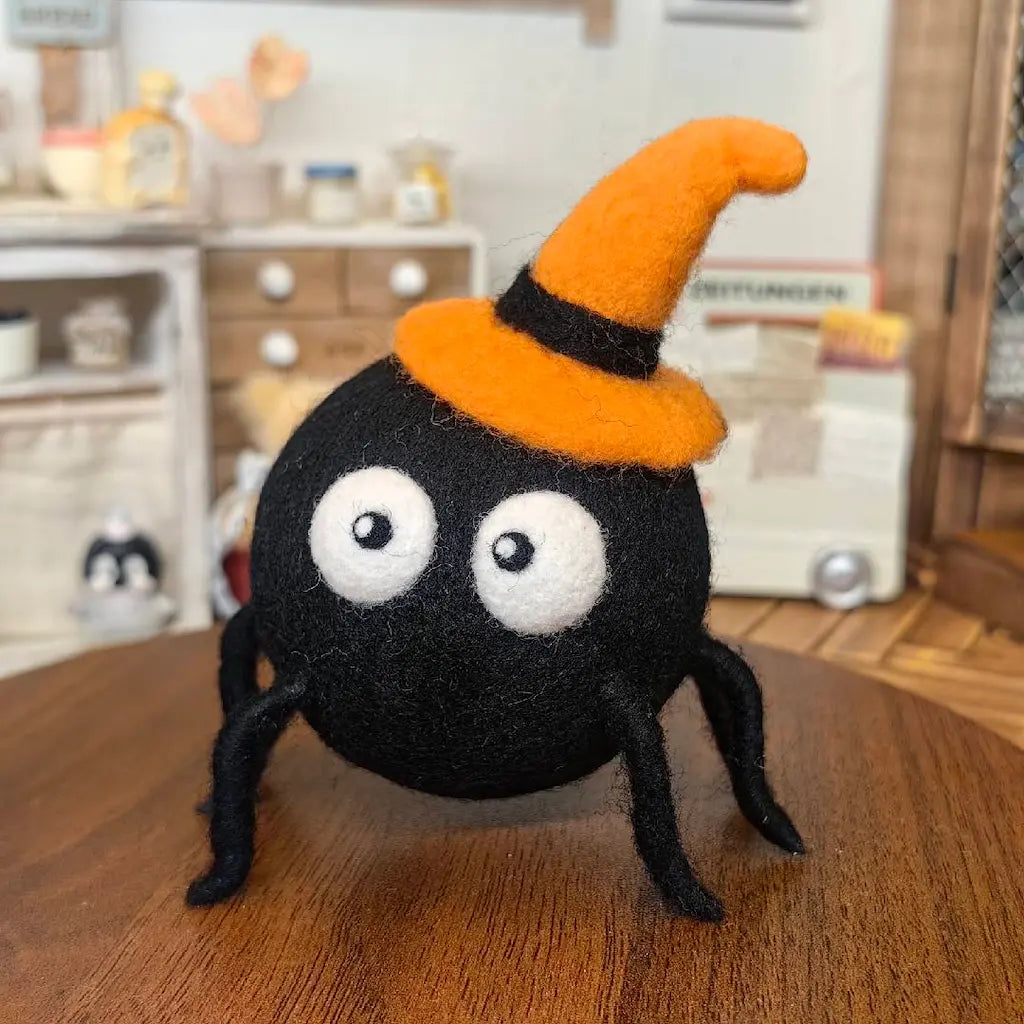 Midnight Spider wool felt figurine wearing an orange witch hat with oversized white eyes