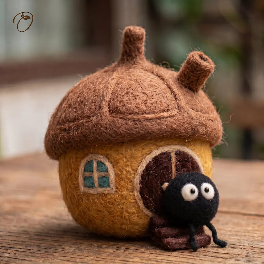 Golden wool felt cottage with an acorn-inspired brown roof and a wide-eyed black Dust Bunny sitting on the front steps.