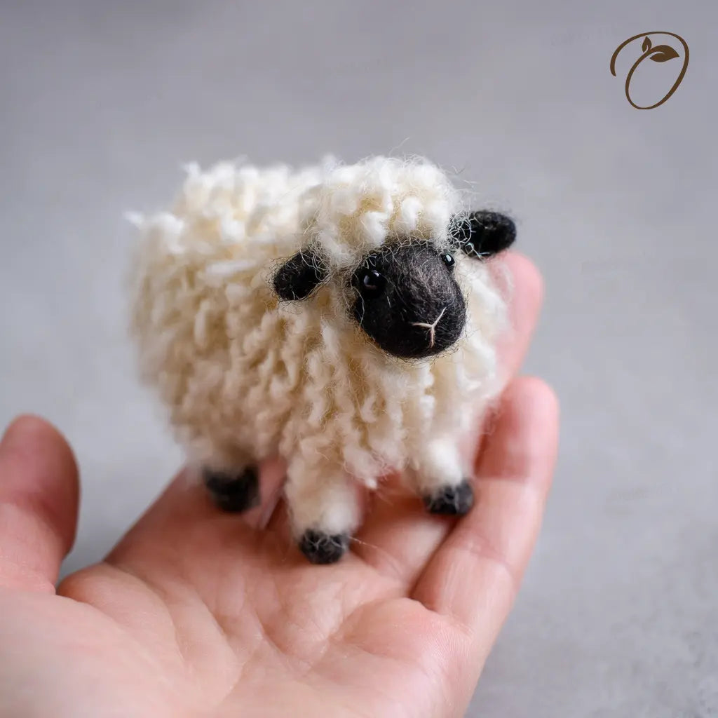 Small knitted sheep held in a hand against a neutral background