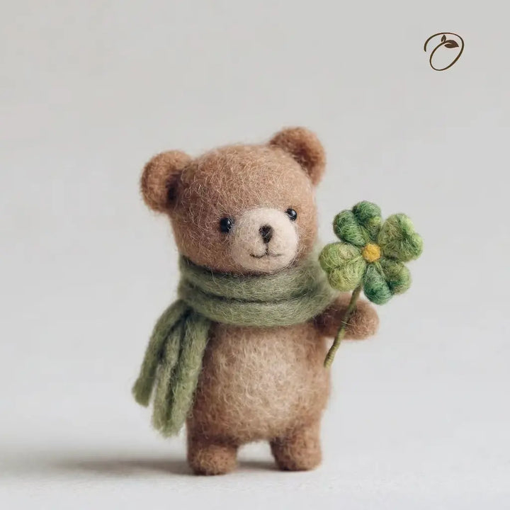 Teddy bear wearing a green scarf and holding a flower on a light background