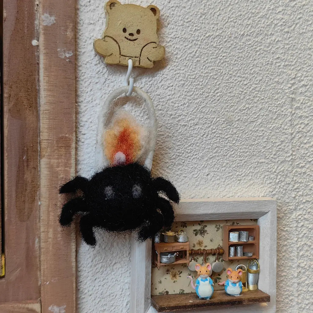 Black spider lantern felt ornament hanging in a miniature cozy room display