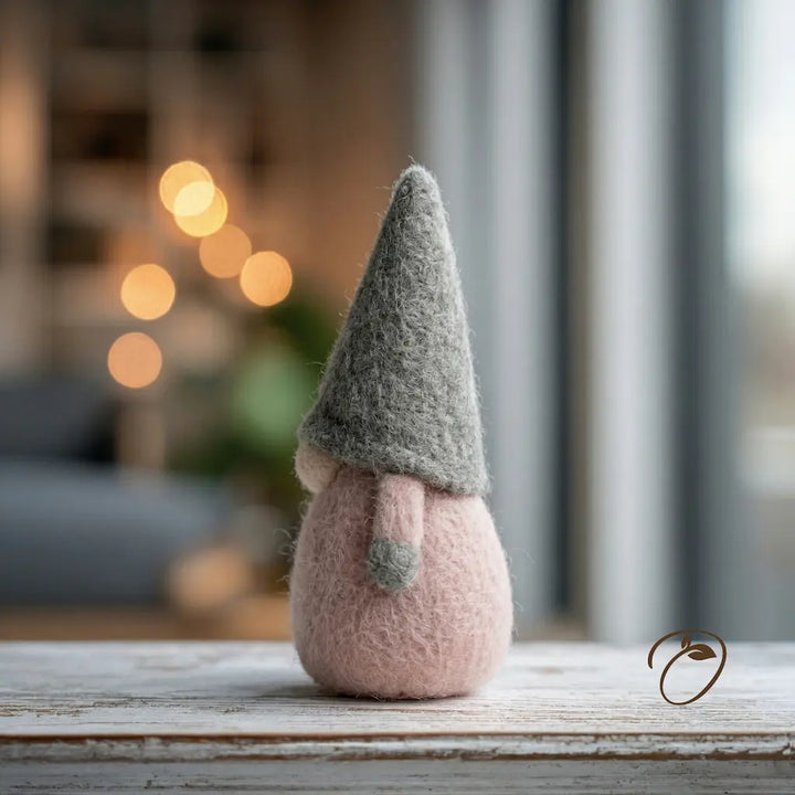 Felted gnome figurine with a gray hat on a wooden surface with a blurred background