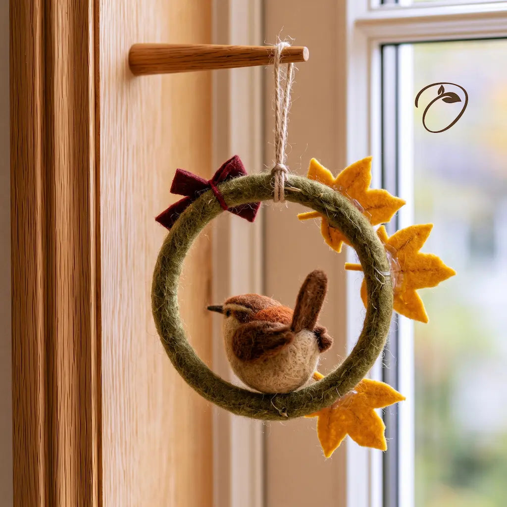 Back view of a felt bird wreath showing the raised tail, green ring, leaf attachments, burgundy bow, and hanging loop.