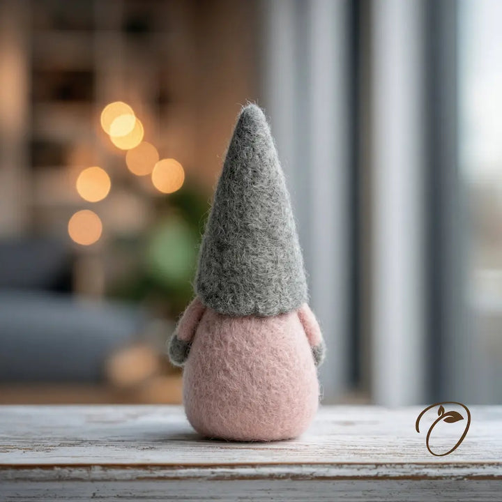 Felted gnome with a gray hat on a wooden surface with a blurred background