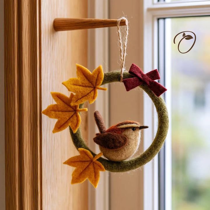 Front view of a green felt wreath with a brown songbird, golden maple leaves, a burgundy bow, and a cord hanging loop.
