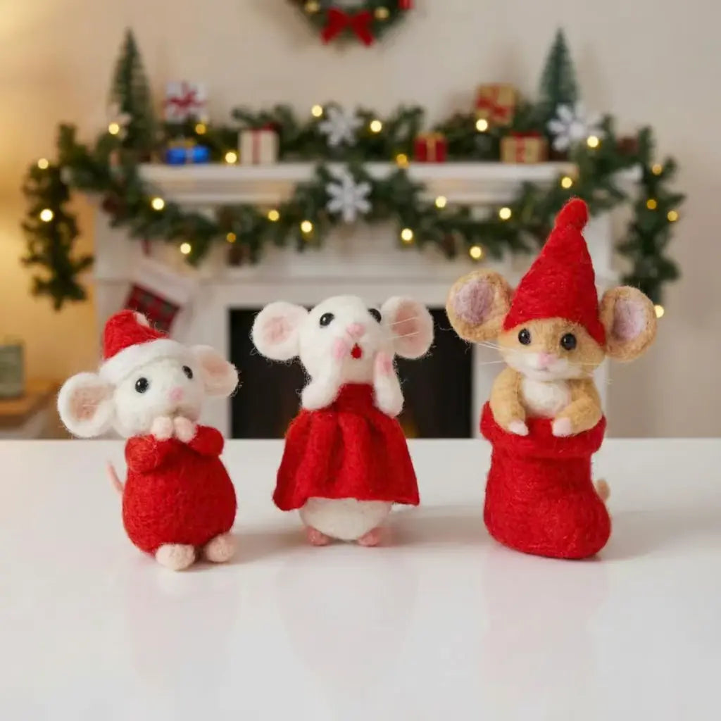 Three small mouse figurines dressed in red outfits and hats on a white surface with a festive background.