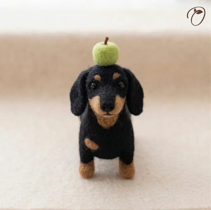 Felted dachshund toy with a green apple on its head against a beige background