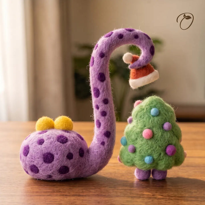 Back view of a spotted purple felt snake curling its tail around a Santa hat beside a green tree with colorful baubles.