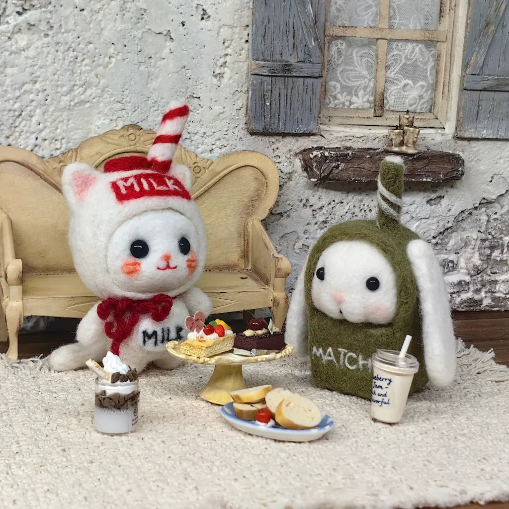Milk Carton Cat and Matcha Bunny felt figurines with miniature cakes and drinks in a cozy cafe scene
