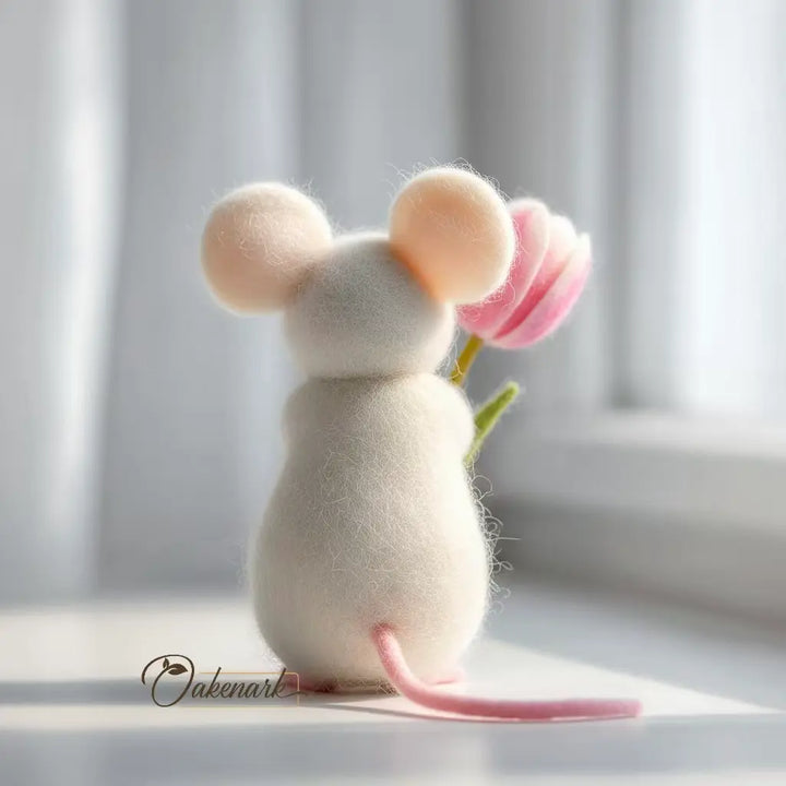 Stuffed mouse toy holding a pink flower on a light background