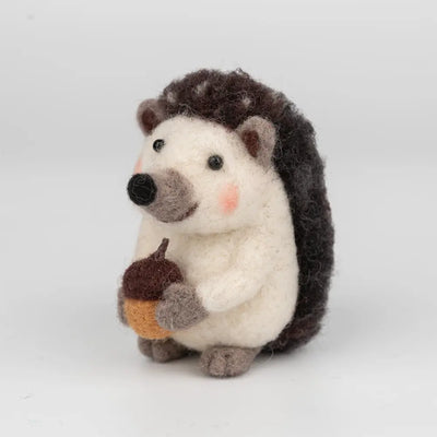 Stuffed hedgehog toy holding an acorn on a white background