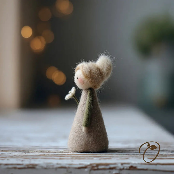 Small figurine of a person with a white flower on a wooden surface with a blurred background
