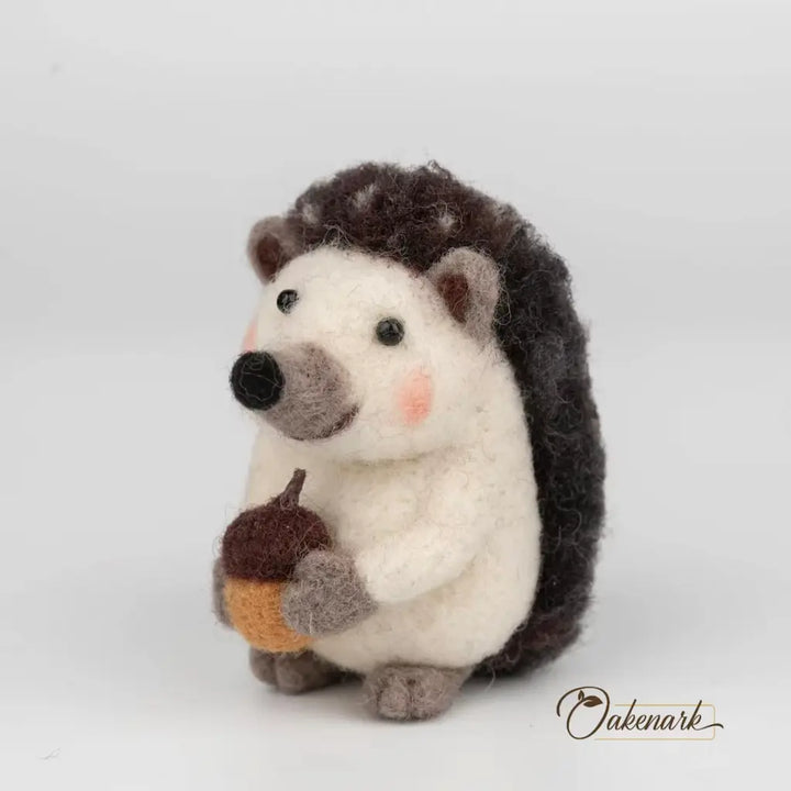 Stuffed hedgehog toy holding an acorn on a white background