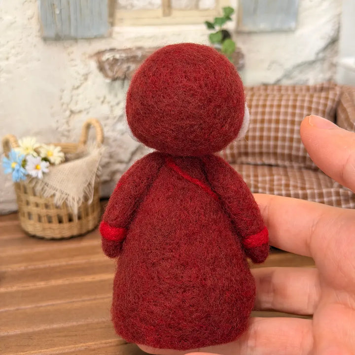 Back view of a handmade Burgundy Bonnet Mrs. Claus wool felt figurine showing her rounded bonnet, burgundy coat, and soft needle-felted texture.