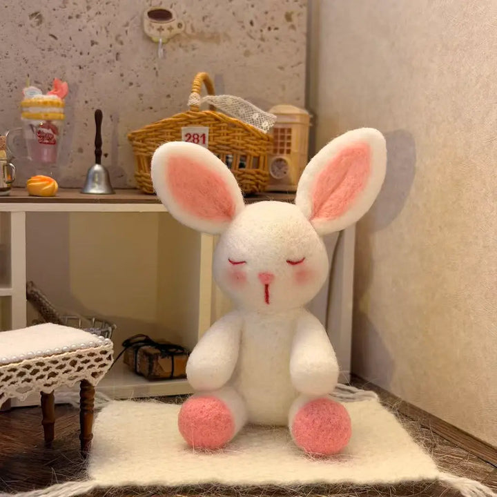 White plush rabbit toy with pink accents sitting on a white rug in a room.