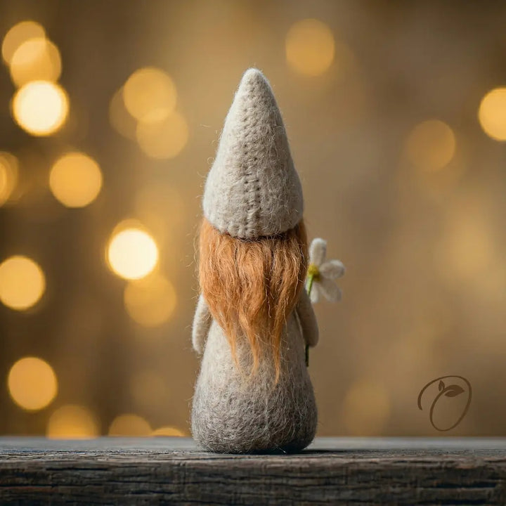 Felted gnome with a flower against a warm, blurred light background