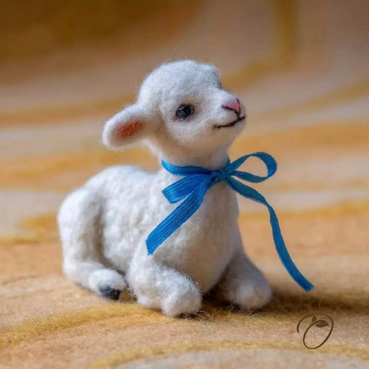 White toy lamb with a blue ribbon on a striped fabric background