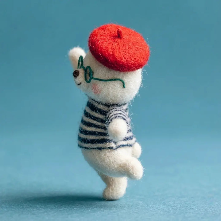Small white figurine with a red beret and striped shirt on a blue background