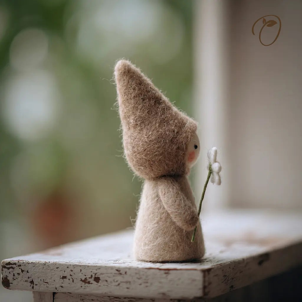 Small gnome figurine holding a flower on a wooden surface with a blurred natural background