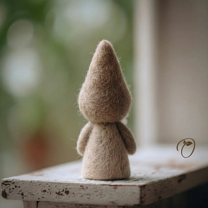 Small brown fiber art figure on a wooden surface with a blurred natural background