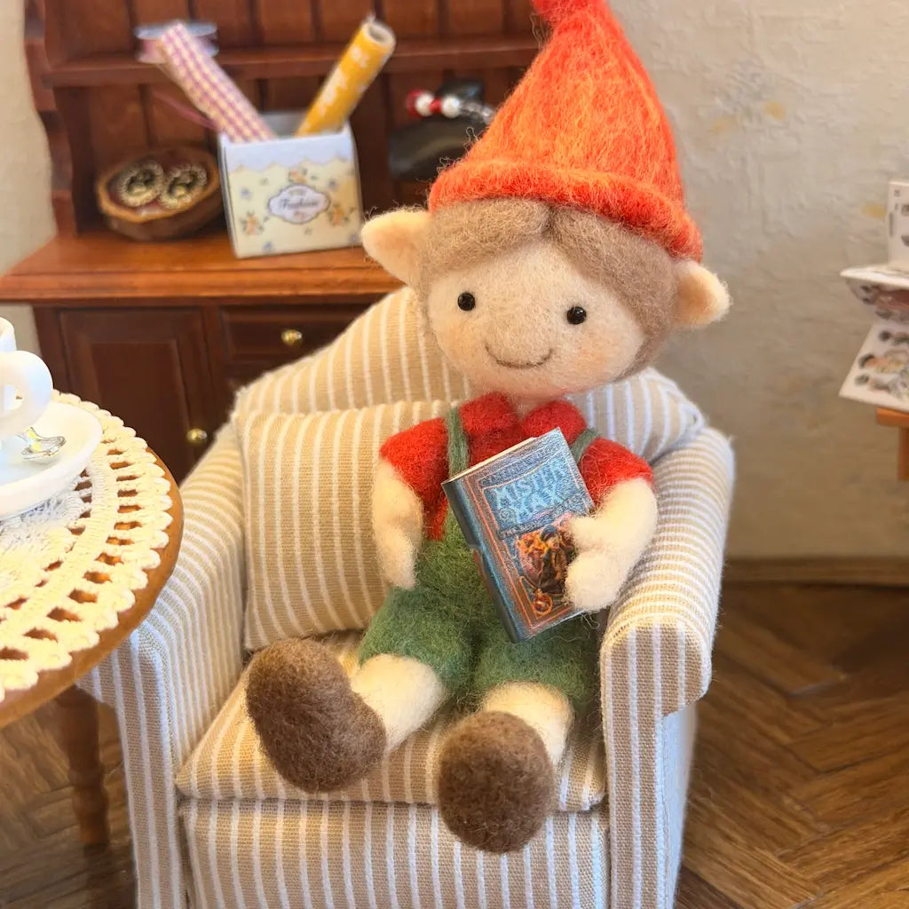 Stuffed elf sitting in a chair holding a book in a cozy room.