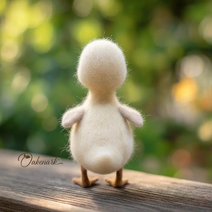 White felted duck toy on a wooden surface with a blurred natural background