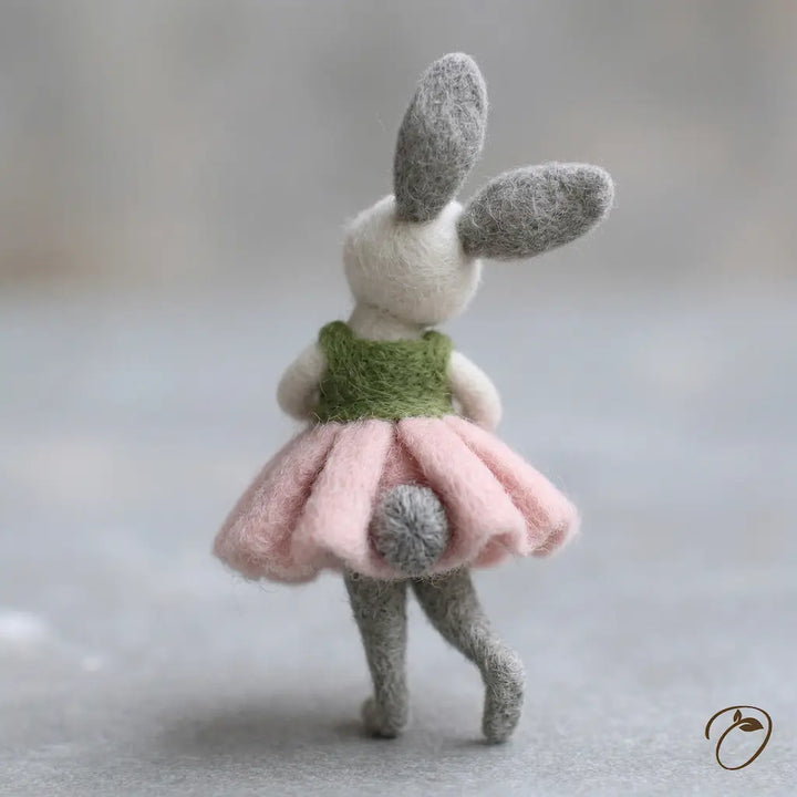 Toy rabbit with a green sweater and pink skirt on a neutral background