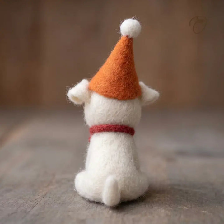 Small white creature with an orange hat and red collar on a wooden surface