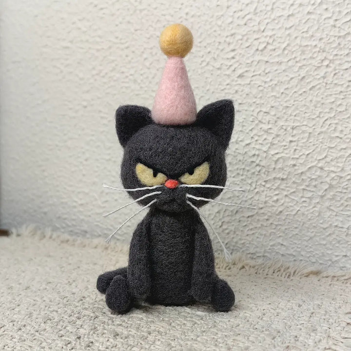 Needle-felted Birthday Mood Cat figurine in dark gray wool with pink party hat, front view