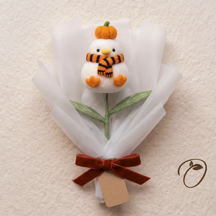 White wool felt chick with a tiny pumpkin on its head and an orange and black scarf, wrapped as a bouquet