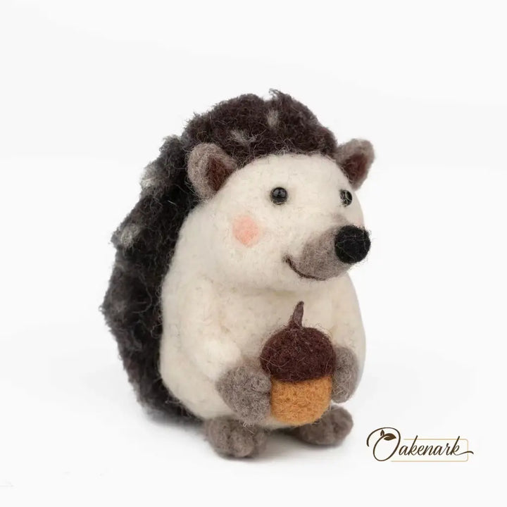 Stuffed hedgehog toy holding an acorn on a white background