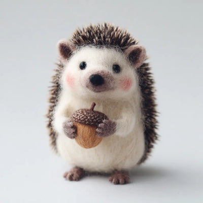 Stuffed hedgehog holding an acorn on a light background