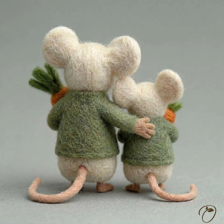 Two plush mice in green sweaters holding carrots on a gray background