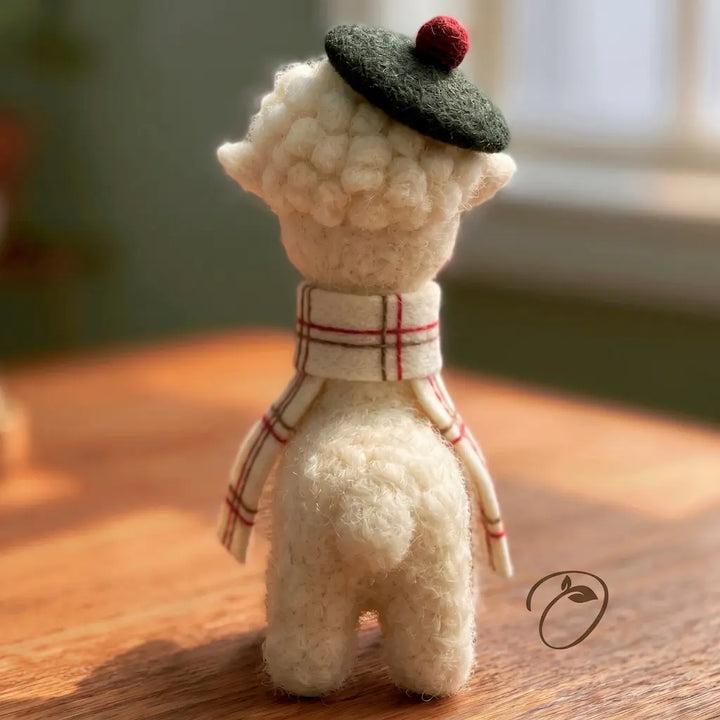 Back view of a handmade alpaca figurine wearing a Highland beret and scarf