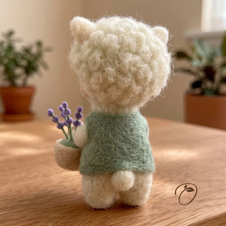 Back view of a handmade alpaca figurine wearing a sage green vest
