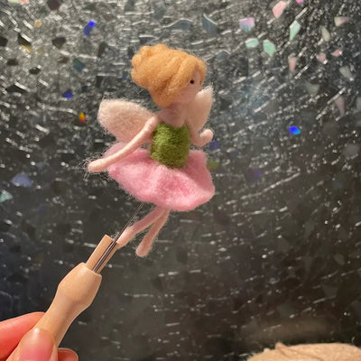 Small fairy figurine held by a hand against a starry night sky background
