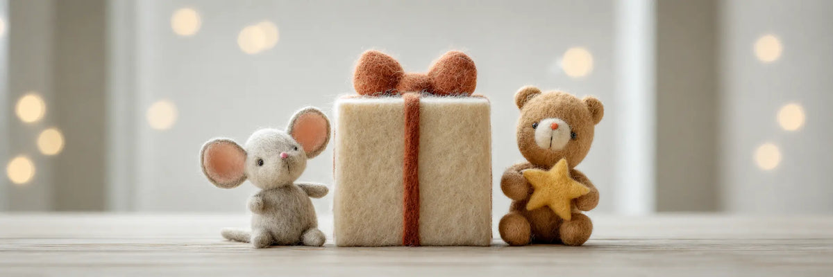 Handmade wool felt mouse and teddy bear beside a wrapped gift box and felt star