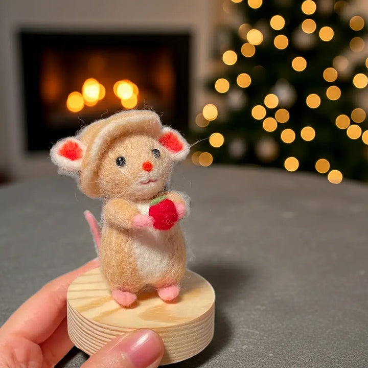 Small plush mouse toy on a wooden base with a blurred festive background