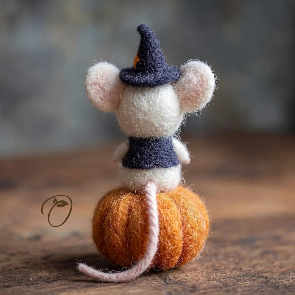 Back view of Halloween mouse felt figurine sitting on an orange pumpkin