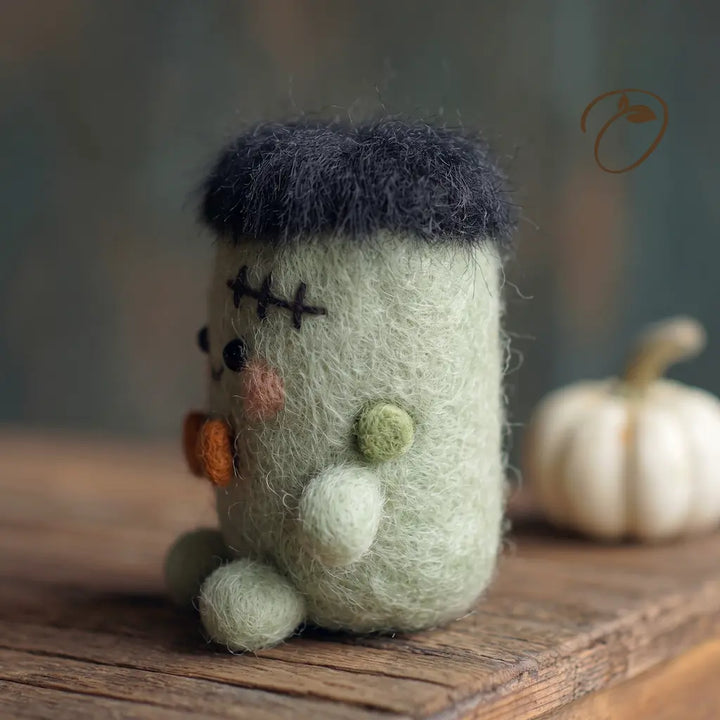 Side view of green Halloween monster felt figurine with black hair and bow tie