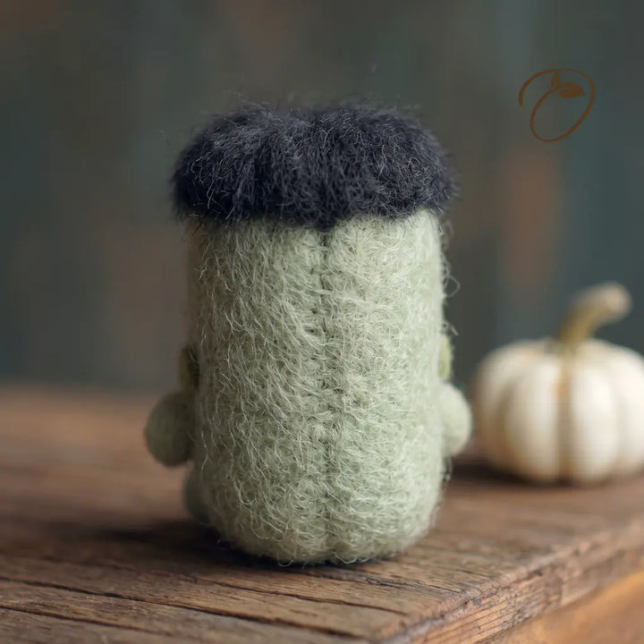Back view of green wool felt Halloween monster figurine with shaggy black hair
